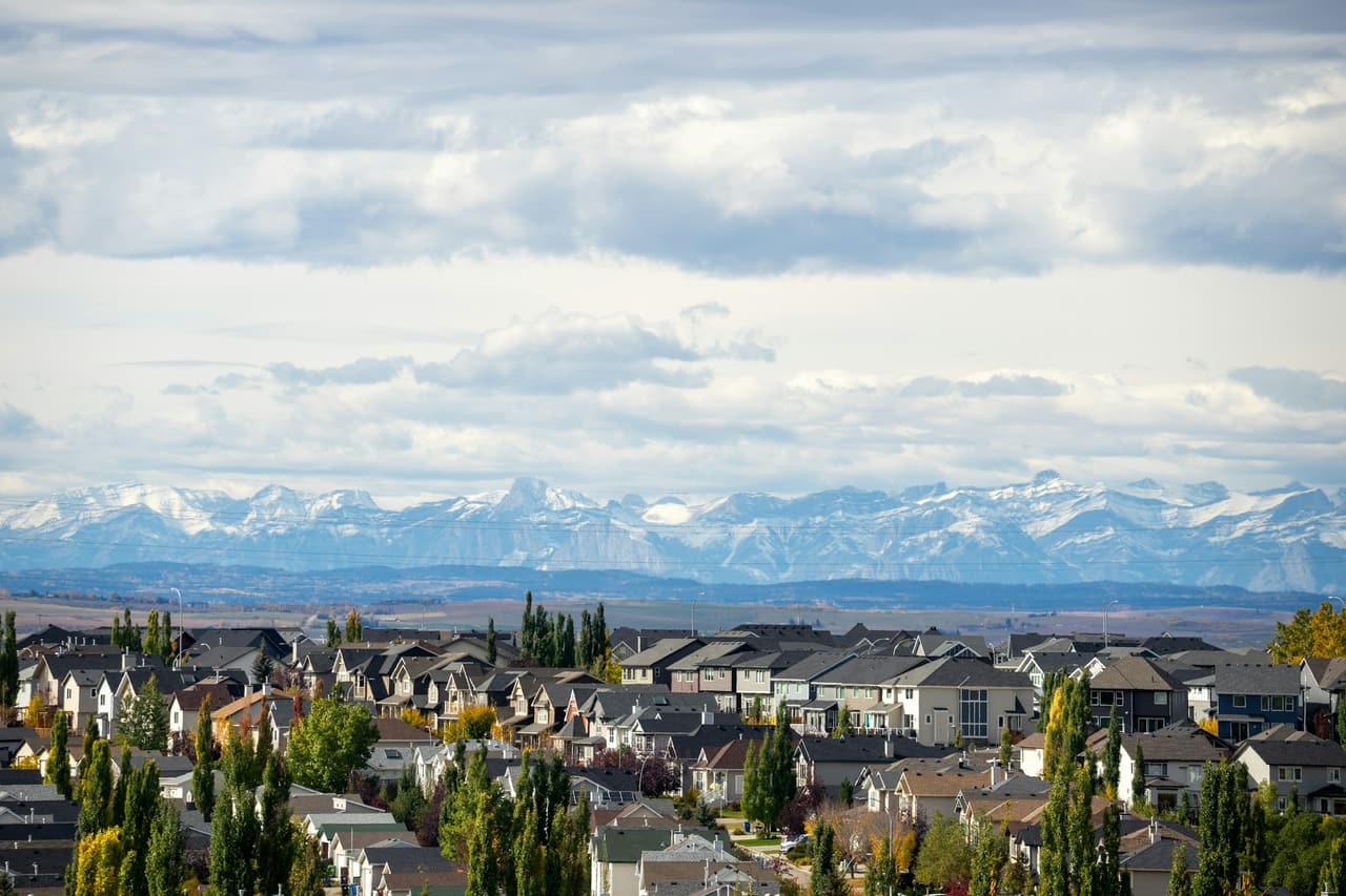 Rooftops of a Calgary suburb with the Rocky Mountains on the horizon