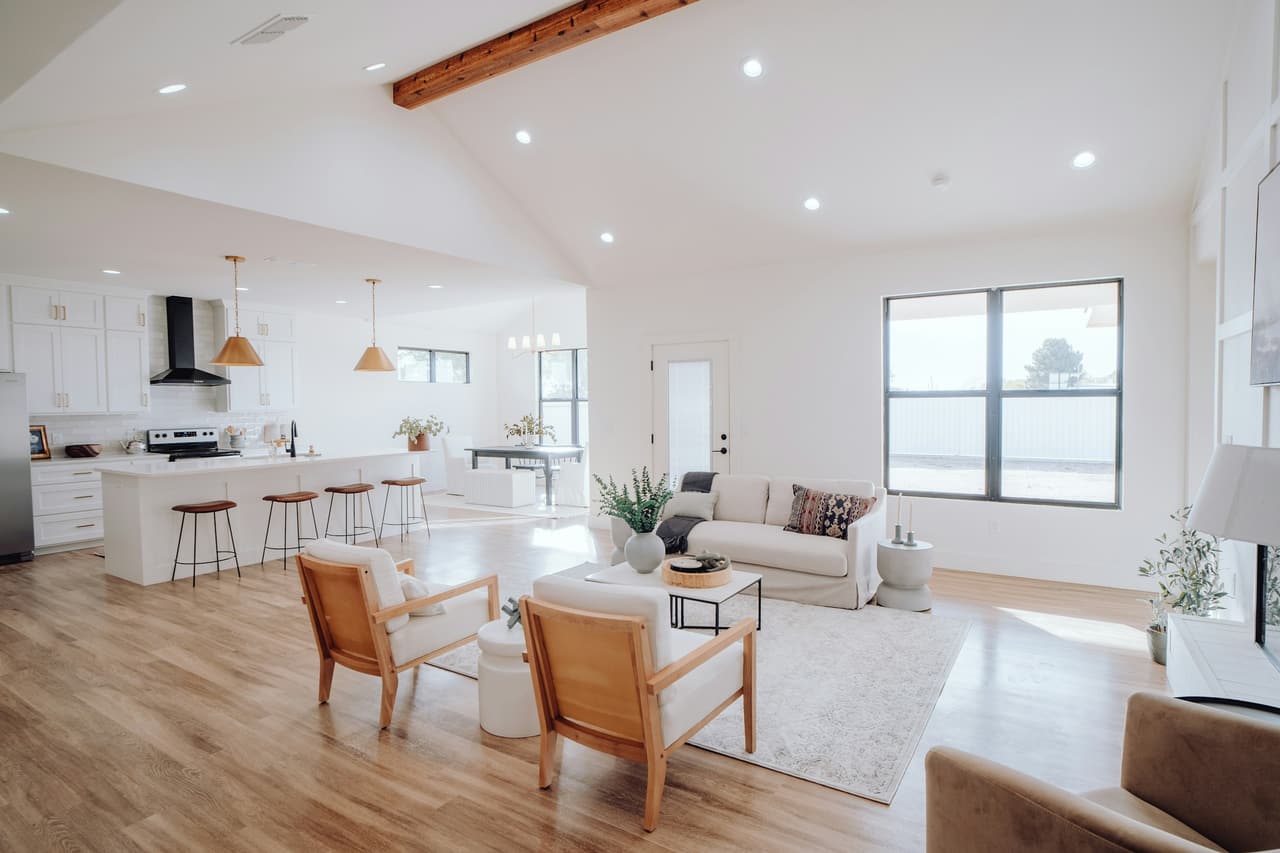 A bright open-plan living room and kitchen in a new home, with light wood floors and large windows